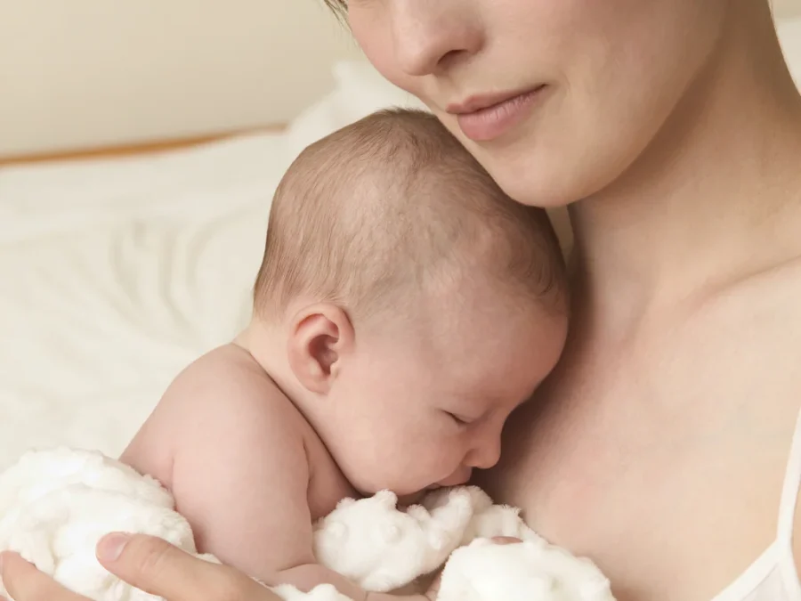 Mãe com o seu bebé recém-nascido ao colo — queda de cabelo pós-parto