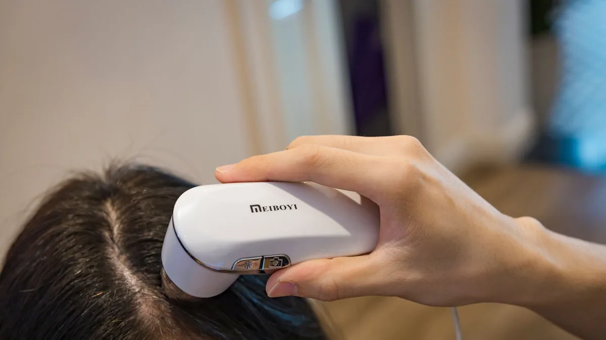 Woman holding a small handheld trichoscope used to examine the scalp and hair before a hair analysis appointment