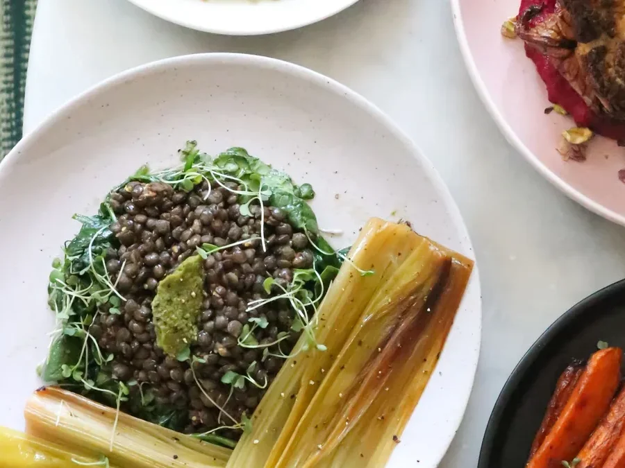 Table with healthy dishes of lentils, leafy greens and vegetables: iron-rich foods for hair health