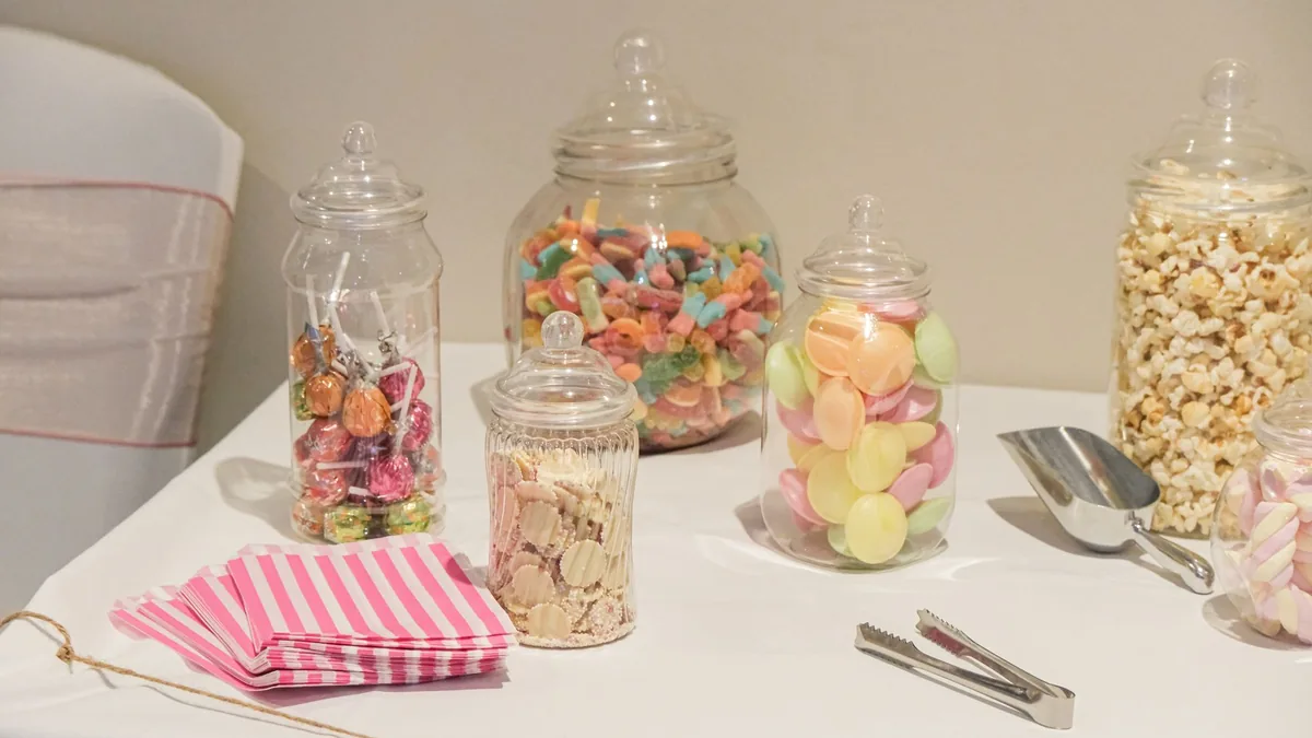Jars of colorful candy, sweets and popcorn on a table – sugary snacks and hair health